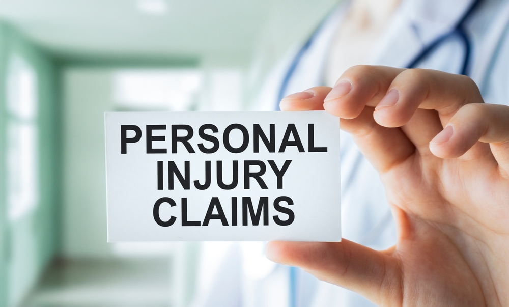 Hand holding a card that reads “Personal Injury Claims,” highlighting the process of filing an injury case