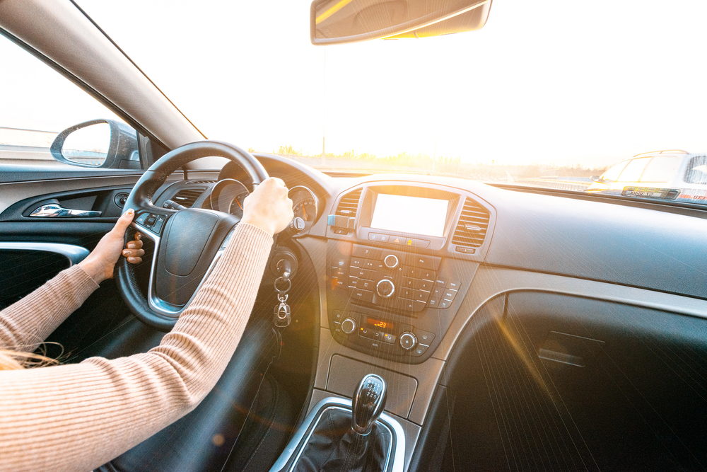 Teen driver holding the steering wheel while driving at sunset