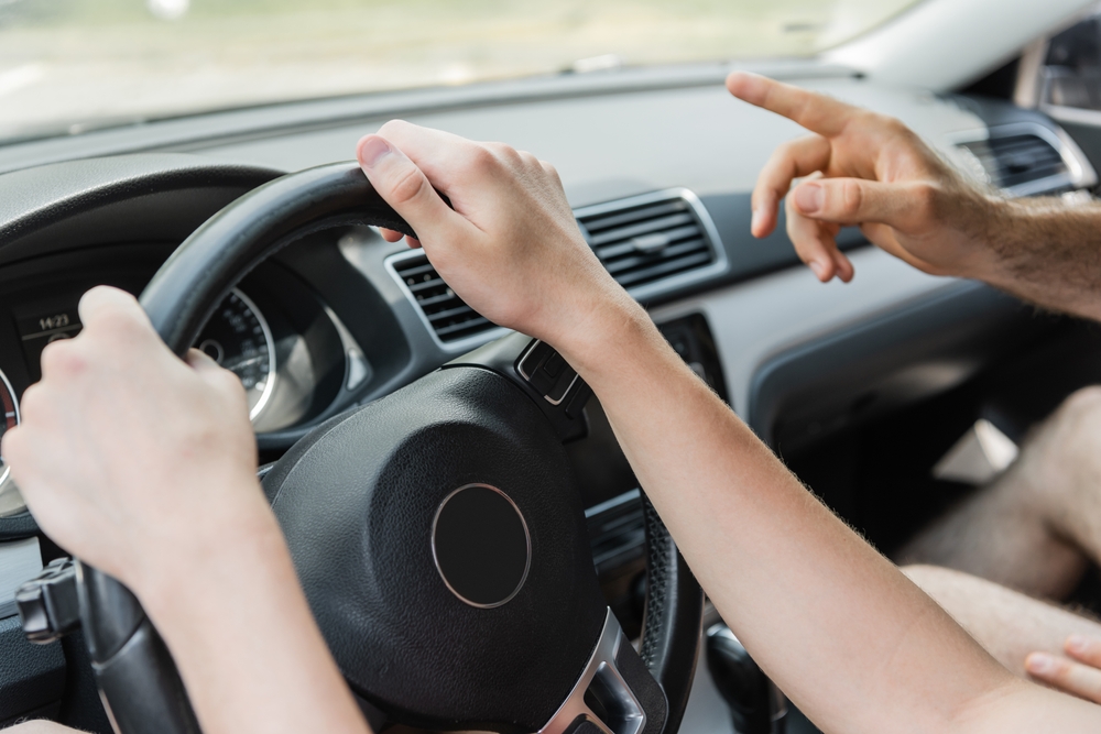 Young driver at the wheel with instructor giving guidance