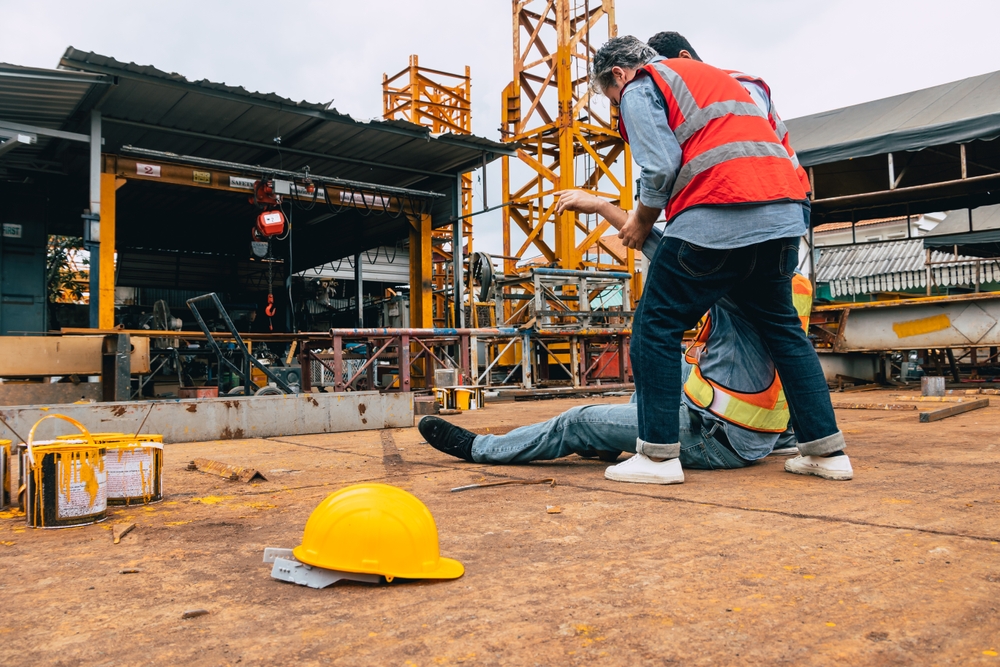 Injured construction worker being assisted by a coworker after an accident at a Massachusetts construction site