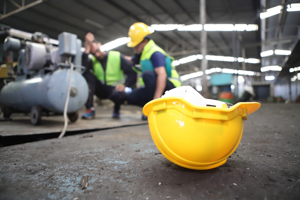 Hard hat on the ground at a construction site with injured workers in the background, illustrating a construction zone injury in Massachusetts.