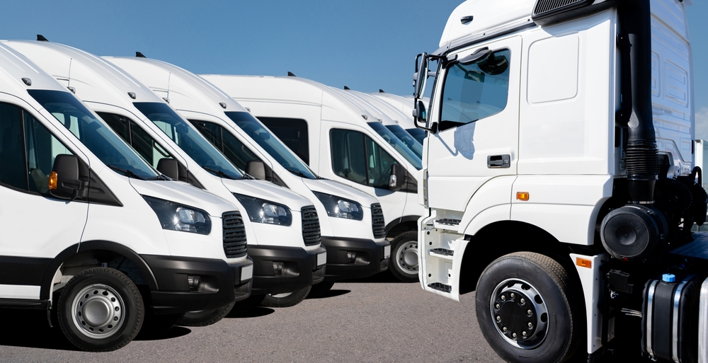 Line of commercial vans and a large truck parked at a transportation facility