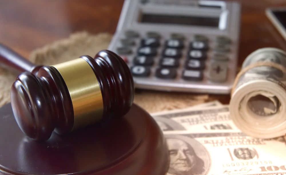 Gavel and calculator resting on U.S. currency representing financial damages after a drunk driving accident in Massachusetts