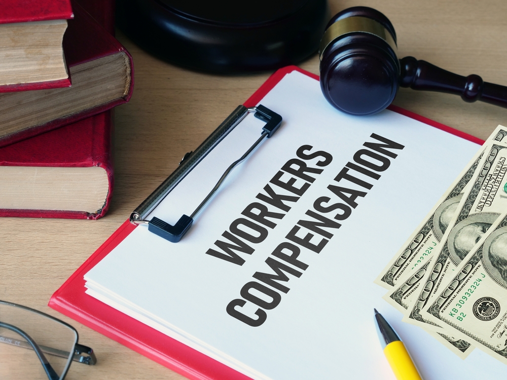 Workers’ compensation claim documents on a desk with a gavel and U.S. currency