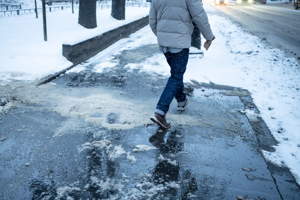 Pedestrian walking on icy sidewalk showing slip and fall risk in Worcester Massachusetts