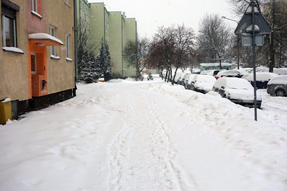 Snow covered sidewalk outside residential buildings illustrating Worcester snow and ice liability