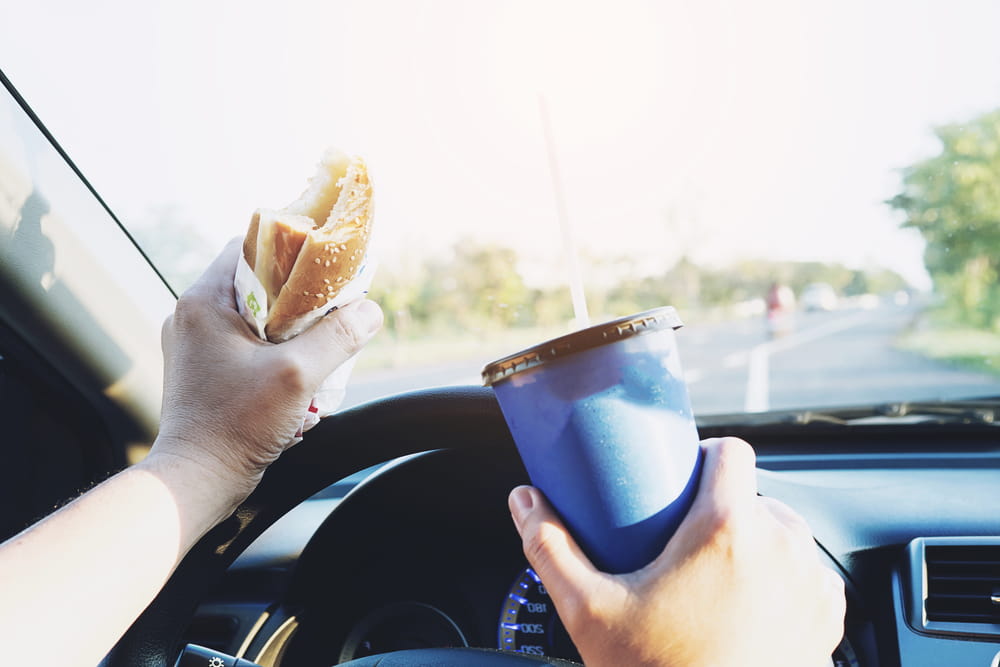 Driver eating and drinking behind the wheel while distracted from the road