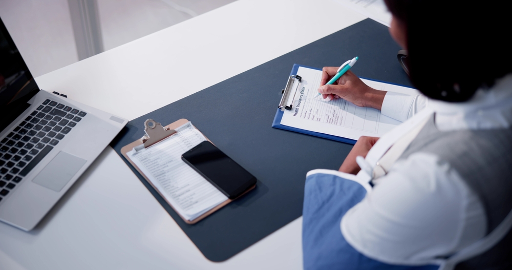 Person with an arm injury filling out an insurance claim form after a rideshare accident